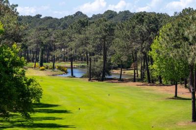 Chambre lumineuse avec lit double, balcon donnant sur un espace arboré, rideaux rouges et lampe de chevet allumée.