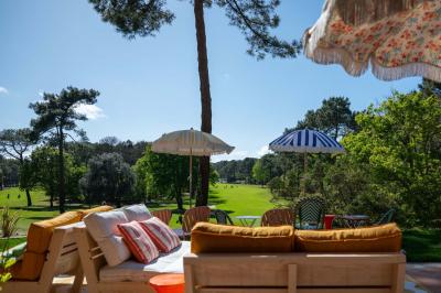Chambre lumineuse avec lit double, balcon donnant sur un espace arboré, rideaux rouges et lampe de chevet allumée.