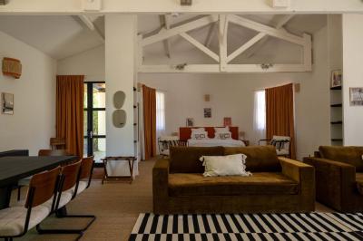 Chambre lumineuse avec lit double, balcon donnant sur un espace arboré, rideaux rouges et lampe de chevet allumée.
