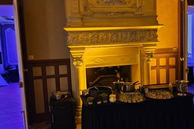 Table dressée avec verres, herbes et ustensiles devant une cheminée décorative dans une pièce éclairée.