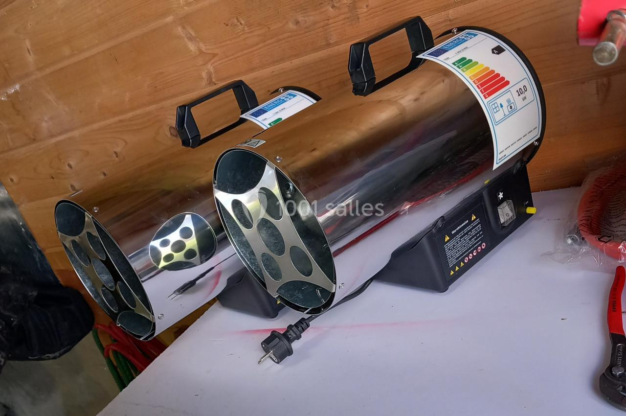 Deux chauffages industriels en métal, posés sur une surface blanche, avec des étiquettes énergétiques visibles.