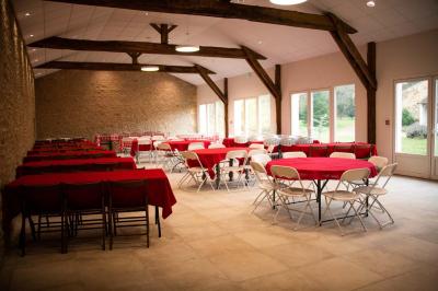 Salle de réception lumineuse avec tables rondes dressées, décorées de fleurs dans un vase central.