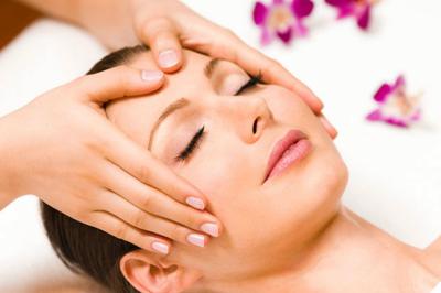 Salle de réception lumineuse avec des tables rondes dressées, des chaises blanches et des chandeliers élégants.