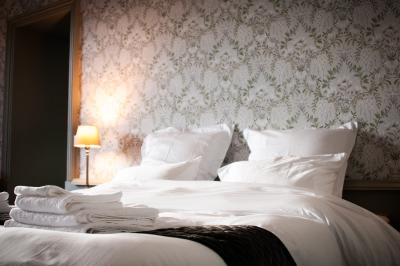 Salle de réception lumineuse avec des tables rondes dressées, des chaises blanches et des chandeliers élégants.