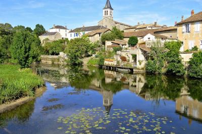 Salle de réception lumineuse avec des tables rondes dressées, des chaises blanches et des chandeliers élégants.