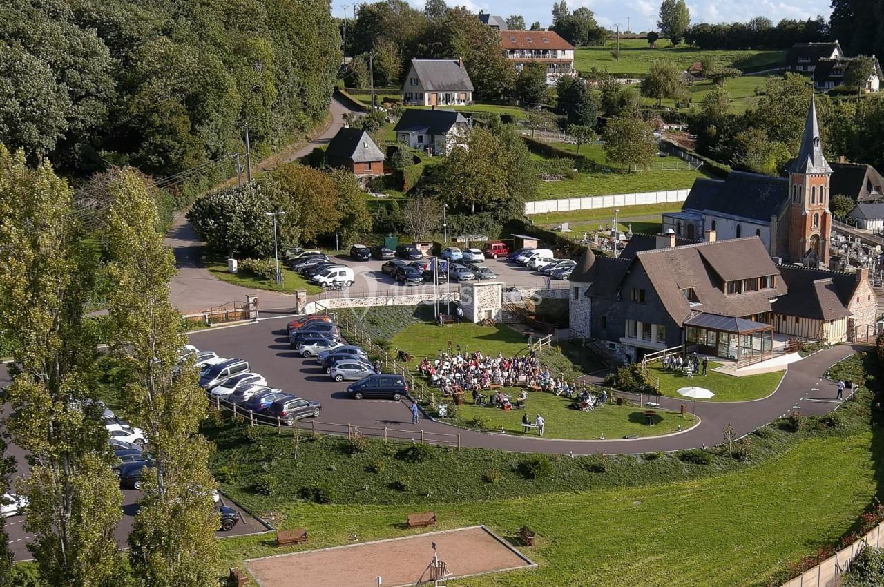 Location salle Saint-Samson-de-la-Roque (Eure) - Manoir Néo Normand #22 Vue aérienne d'un village avec une église, un parking, une aire de jeux et un rassemblement en plein air.