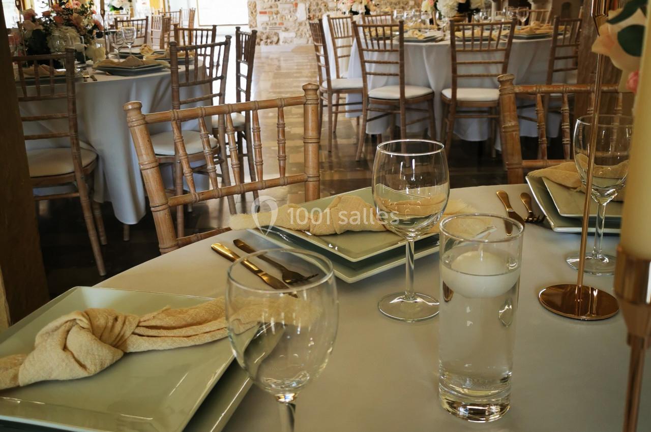 Location salle Saint-Samson-de-la-Roque (Eure) - Manoir Néo Normand #24 Salle de réception avec tables dressées, nappes blanches, verres, assiettes et décorations florales dans un cadre rustique.