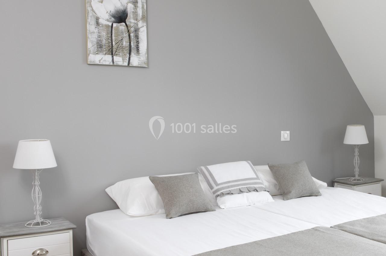 Location salle Saint-Samson-de-la-Roque (Eure) - Manoir Néo Normand #71 Lit double avec linge de lit gris et blanc, encadré par deux tables de chevet assorties avec lampes, dans une chambre…