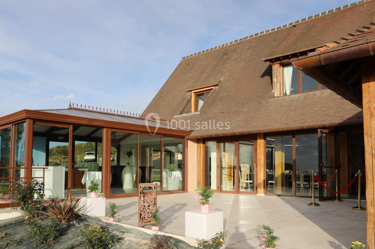 Location salle Saint-Samson-de-la-Roque (Eure) - Manoir Néo Normand #44 Façade d'un bâtiment avec une véranda vitrée, des plantes décoratives et une entrée aménagée pour des événements.