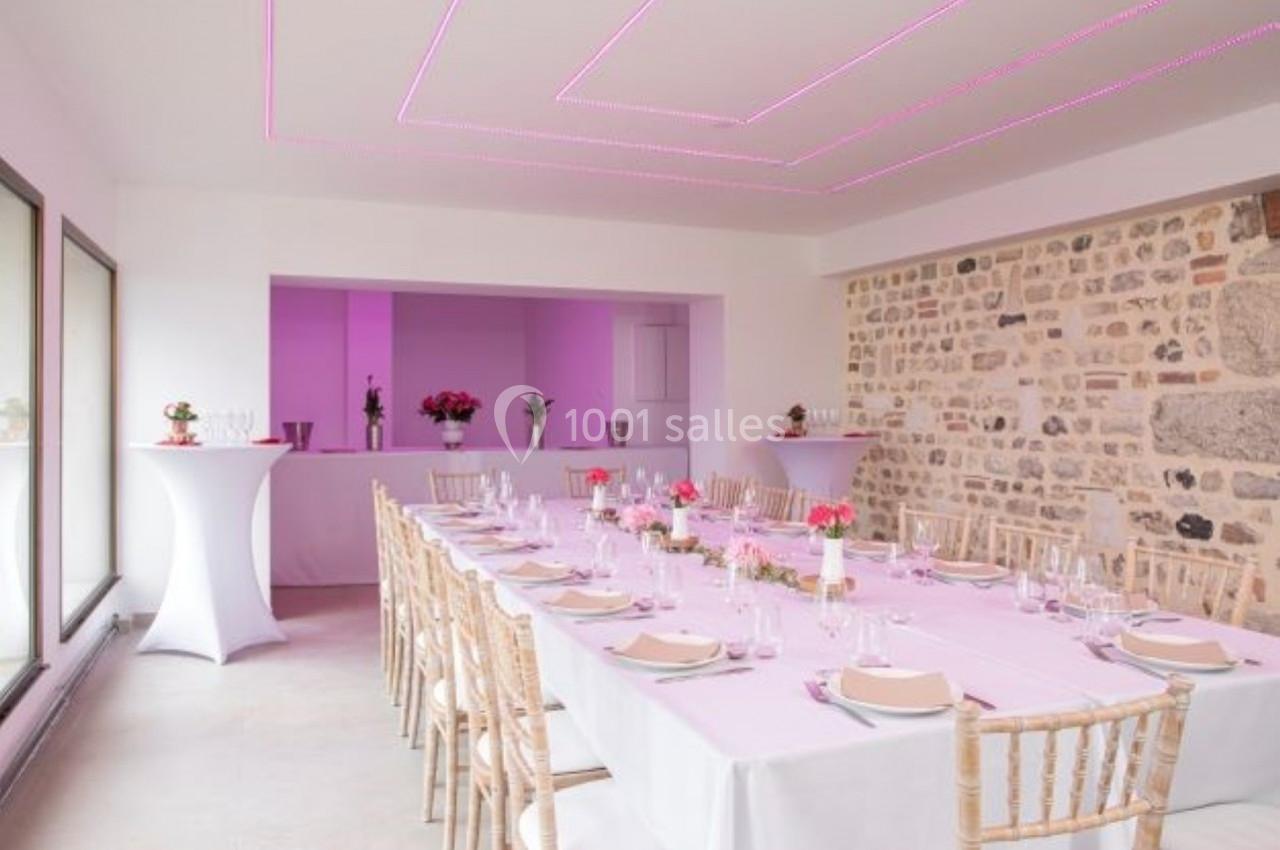 Location salle Saint-Samson-de-la-Roque (Eure) - Manoir Néo Normand #13 Salle de réception lumineuse avec une longue table dressée, décorée de fleurs roses et éclairée par des lumières violettes.