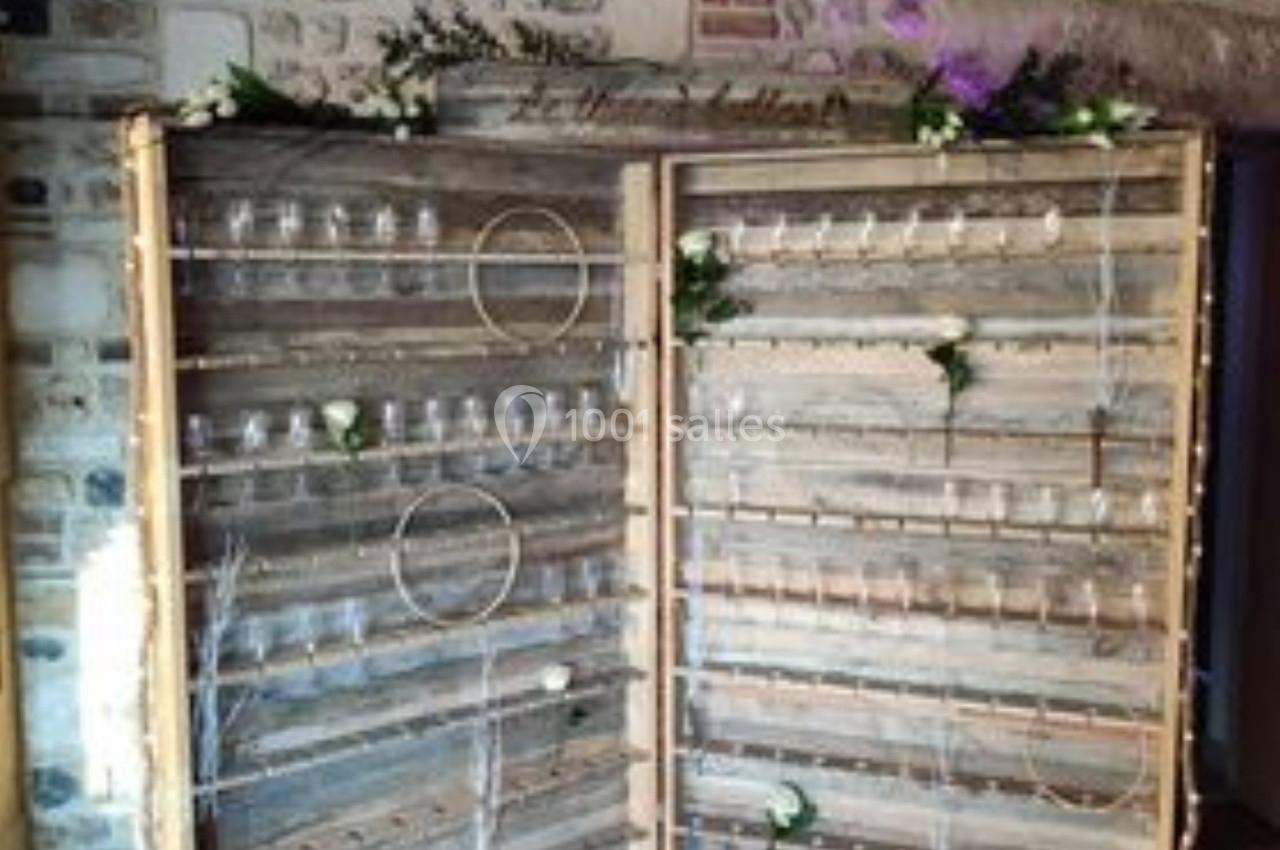 Location salle Saint-Samson-de-la-Roque (Eure) - Manoir Néo Normand #11 Mur en bois décoratif avec des étagères contenant des verres et des fleurs, installé dans une pièce en pierre apparente.