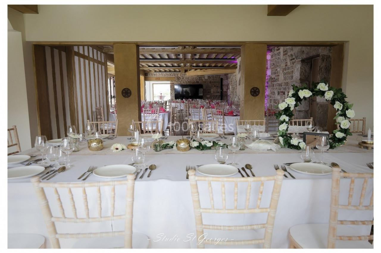 Location salle Saint-Samson-de-la-Roque (Eure) - Manoir Néo Normand #79 Table de réception élégamment dressée avec des chaises en bois clair, décorations florales et vue sur une salle en pierre.