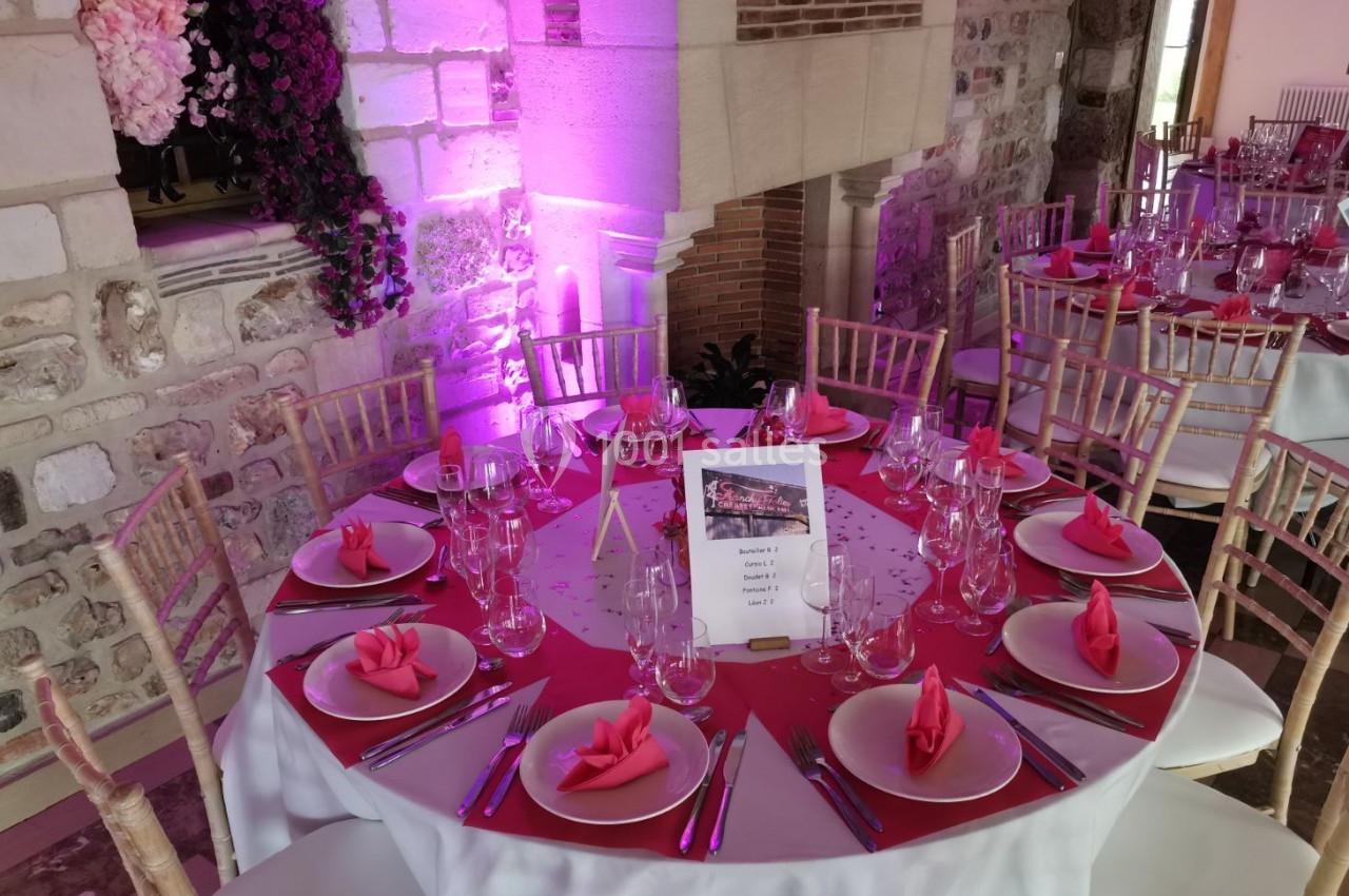 Location salle Saint-Samson-de-la-Roque (Eure) - Manoir Néo Normand #16 Table ronde décorée pour un événement, avec nappes roses, serviettes pliées, verres et couverts, dans une salle en pierre.
