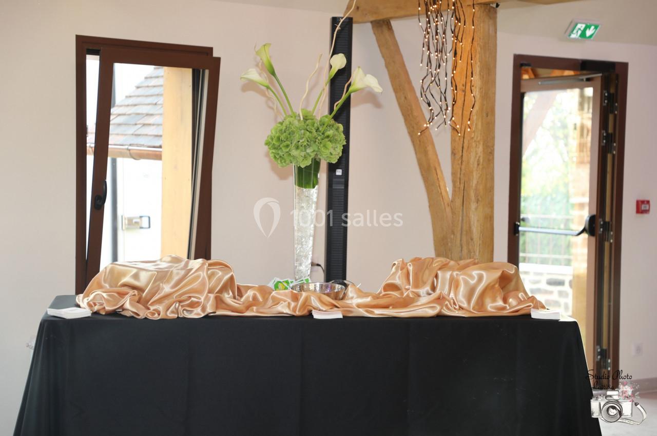 Location salle Saint-Samson-de-la-Roque (Eure) - Manoir Néo Normand #94 Vase avec des fleurs blanches et vertes sur une table décorée de tissu doré dans une salle lumineuse.
