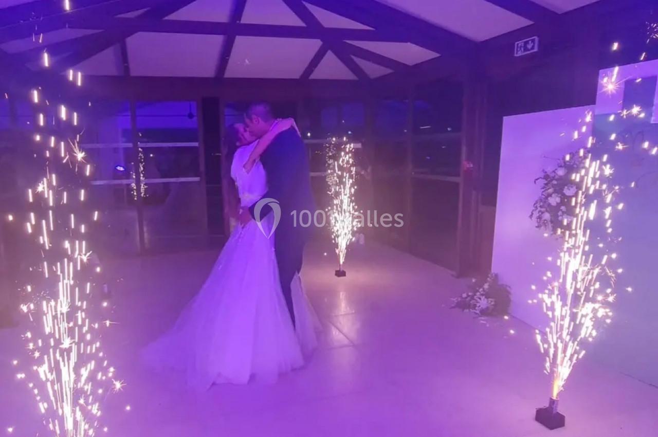 Location salle Saint-Samson-de-la-Roque (Eure) - Manoir Néo Normand #14 Un couple de mariés danse sous des étincelles lumineuses dans une salle éclairée par une lumière violette.