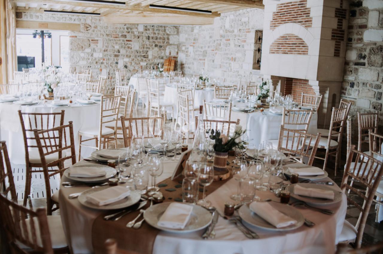Location salle Saint-Samson-de-la-Roque (Eure) - Manoir Néo Normand #27 Salle de réception lumineuse avec des tables rondes décorées pour un événement, entourées de chaises en bois.