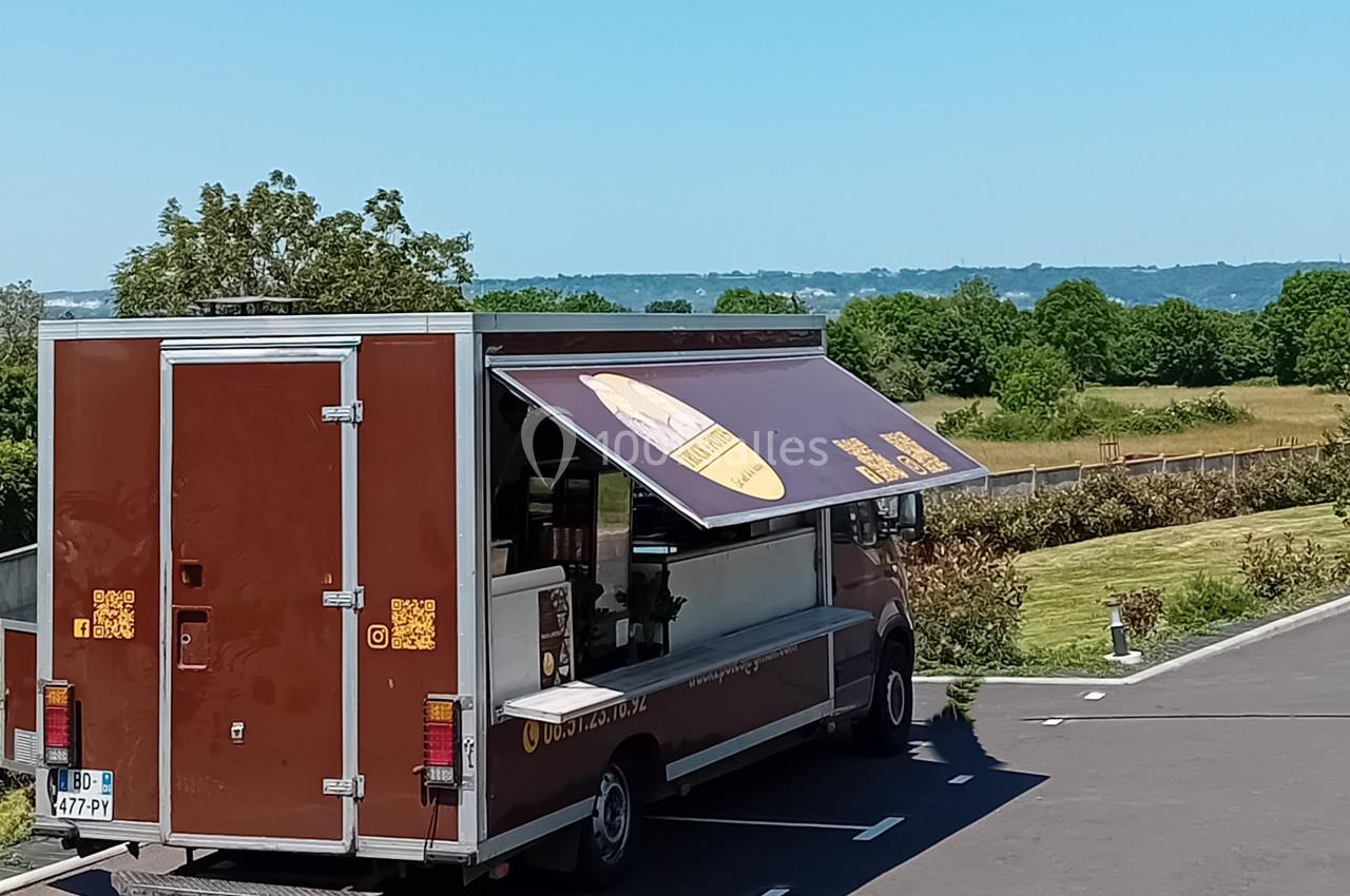 Location salle Saint-Samson-de-la-Roque (Eure) - Manoir Néo Normand #96 Camion de restauration marron stationné sur un parking, avec un auvent déployé et un paysage rural en arrière-plan.