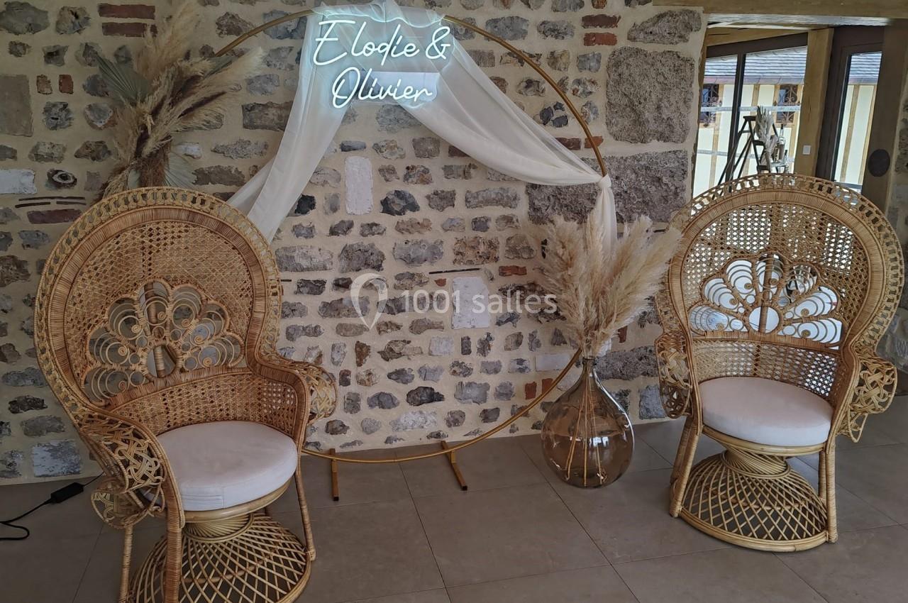 Location salle Saint-Samson-de-la-Roque (Eure) - Manoir Néo Normand #3 Deux fauteuils en rotin devant un mur en pierre, décorés avec un cercle orné de voilages et de pampas.