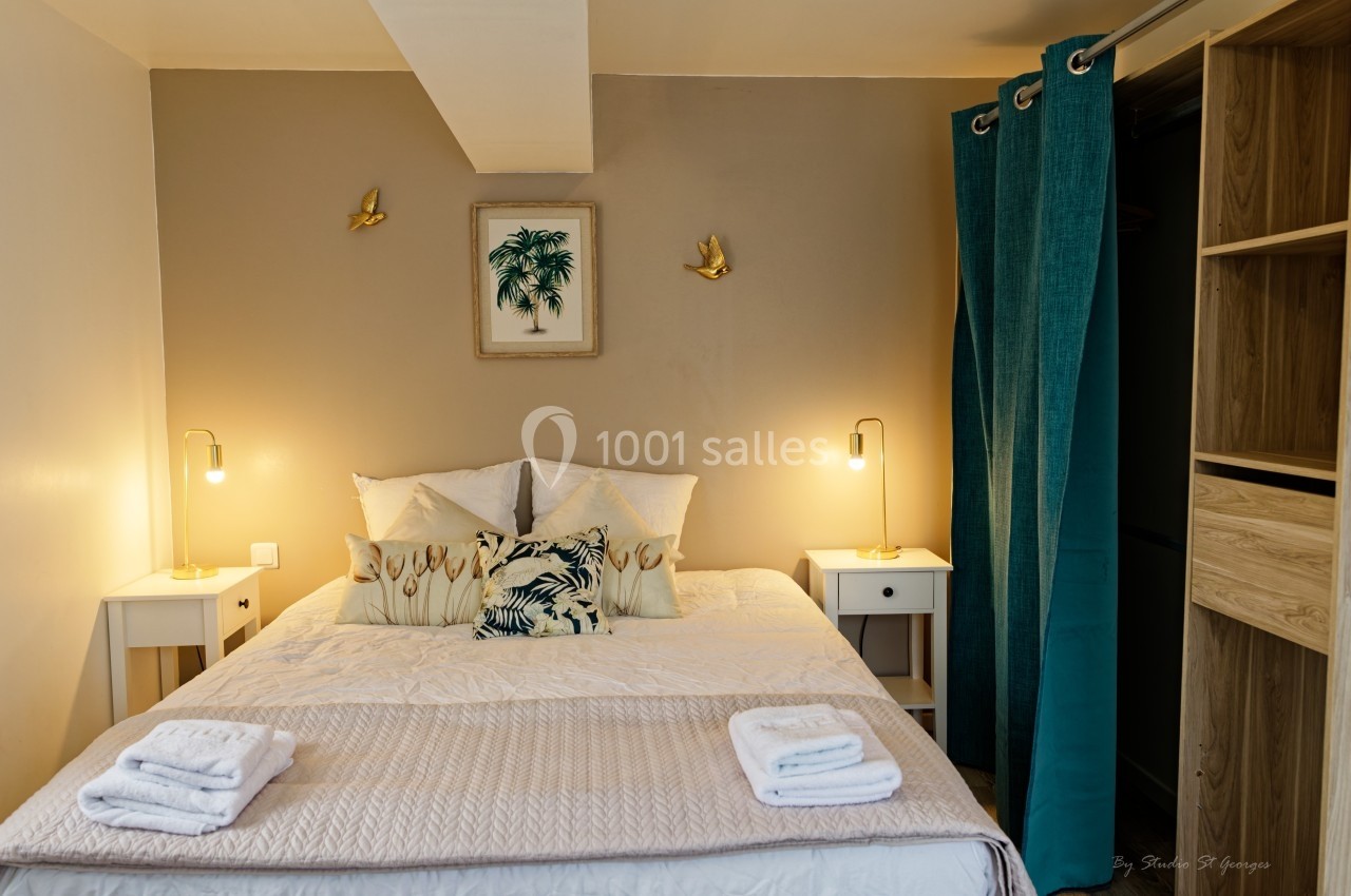 Chambre avec lit double, tables de chevet, lampes allumées, décoration murale et rideaux turquoise.