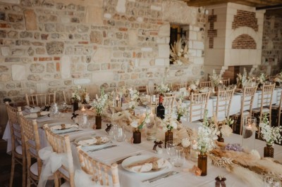 Table dressée en extérieur avec macarons, amuse-bouches, deux verres de champagne et une décoration florale rouge.