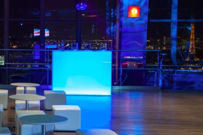 Vue aérienne de Paris au crépuscule, avec la tour Eiffel illuminée et les Invalides visibles au premier plan.