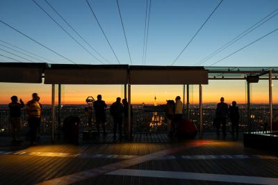 Vue aérienne de Paris au crépuscule, avec la tour Eiffel illuminée et les Invalides visibles au premier plan.