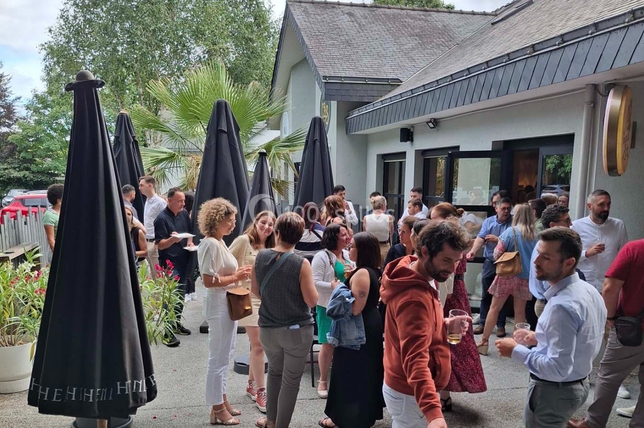Groupe de personnes discutant et partageant un moment convivial sur une terrasse extérieure près d'un bâtiment.