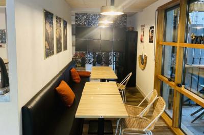 Salle lumineuse avec tables blanches, chaises noires, décoration murale hexagonale et coin détente avec fauteuil jaune.