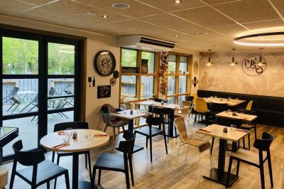 Salle lumineuse avec tables blanches, chaises noires, décoration murale hexagonale et coin détente avec fauteuil jaune.