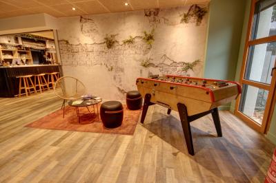 Salle lumineuse avec tables blanches, chaises noires, décoration murale hexagonale et coin détente avec fauteuil jaune.