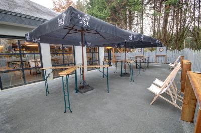 Salle lumineuse avec tables blanches, chaises noires, décoration murale hexagonale et coin détente avec fauteuil jaune.