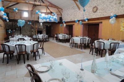 Salle de réception avec tables rondes dressées, nappes noires, chemins de table argentés et décorations florales.