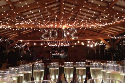 Salle de réception avec tables rondes dressées, nappes noires, chemins de table argentés et décorations florales.