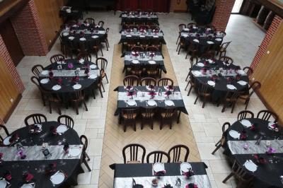 Salle de réception avec tables rondes dressées, nappes noires, chemins de table argentés et décorations florales.