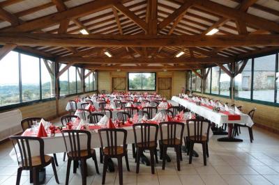 Salle de réception avec tables rondes dressées, nappes noires, chemins de table argentés et décorations florales.