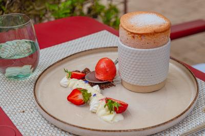 Soufflé servi avec des fraises, crème chantilly, crumble et sorbet, présenté sur une assiette élégante.