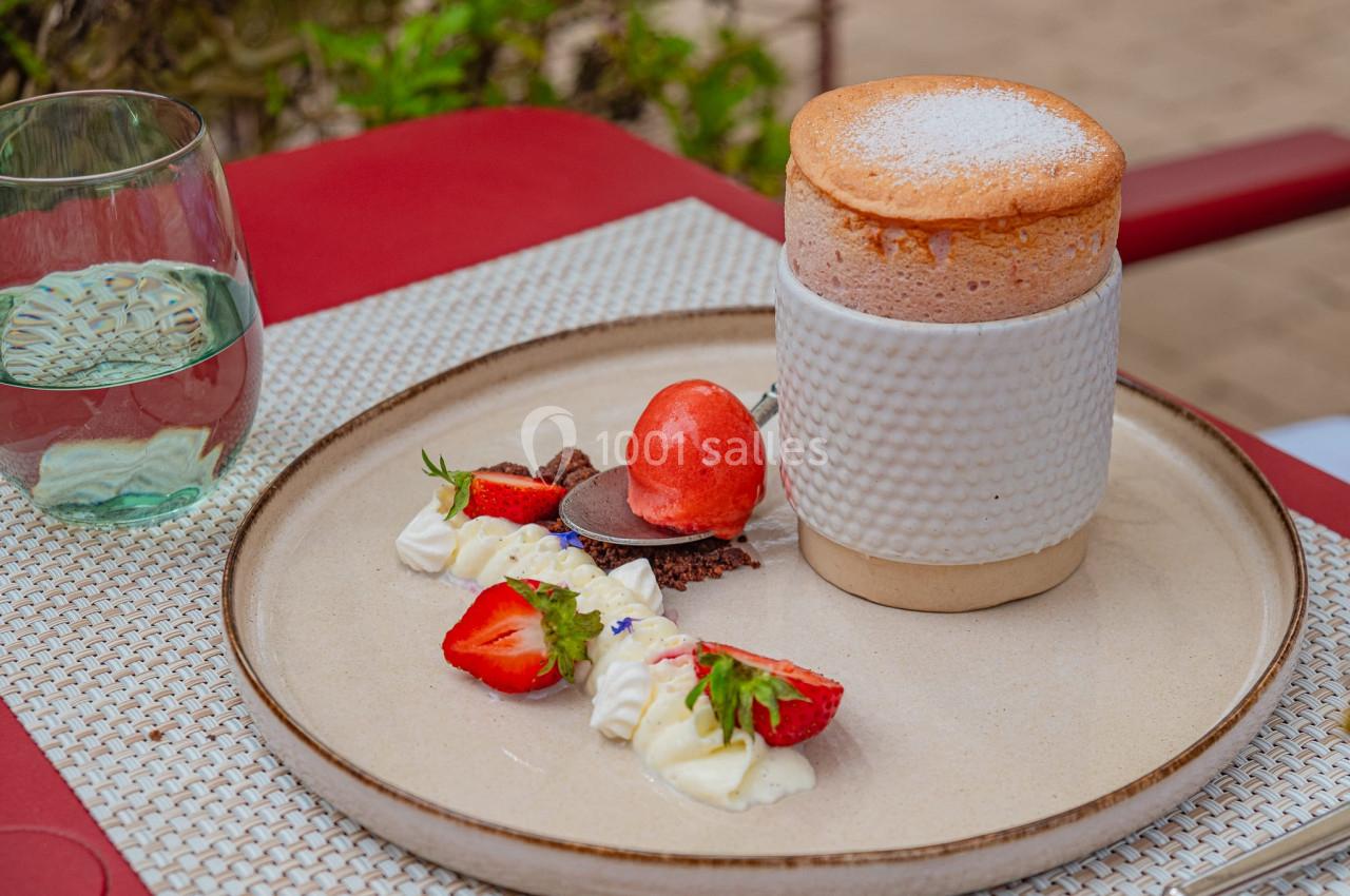 Soufflé servi avec des fraises, crème chantilly, crumble et sorbet, présenté sur une assiette élégante.