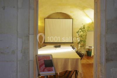 Salle voûtée avec murs en pierre, tables et chaises modernes, buffet en arrière-plan et éclairage chaleureux.