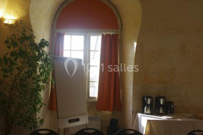 Salle voûtée avec murs en pierre, tables et chaises modernes, buffet en arrière-plan et éclairage chaleureux.