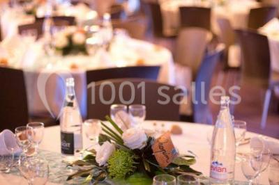 Salle voûtée avec murs en pierre, tables et chaises modernes, buffet en arrière-plan et éclairage chaleureux.