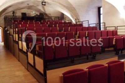 Salle voûtée avec murs en pierre, tables et chaises modernes, buffet en arrière-plan et éclairage chaleureux.