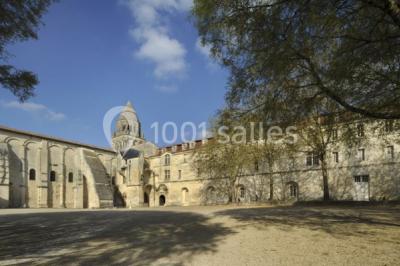 Salle voûtée avec murs en pierre, tables et chaises modernes, buffet en arrière-plan et éclairage chaleureux.