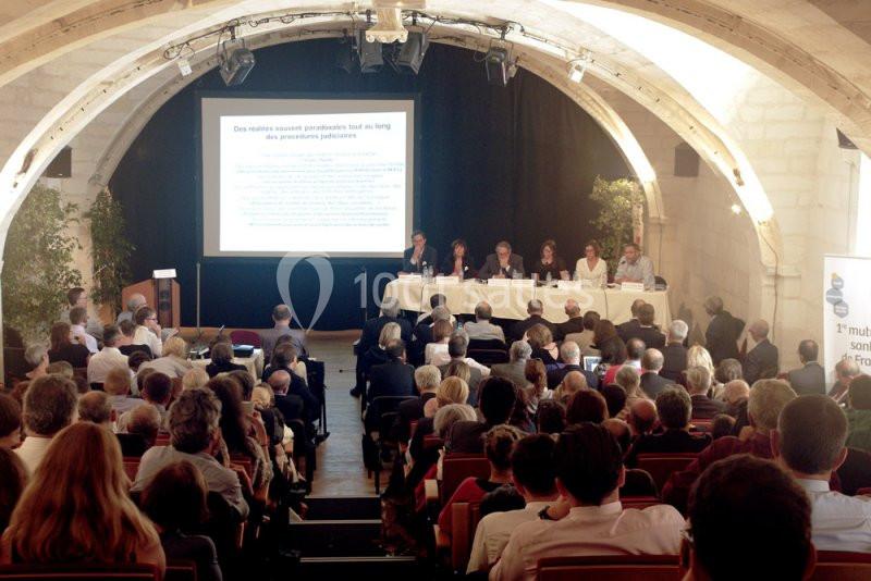 Une conférence avec plusieurs intervenants assis à une table face à un public dans une salle voûtée.