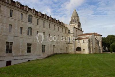 Salle voûtée avec murs en pierre, tables et chaises modernes, buffet en arrière-plan et éclairage chaleureux.
