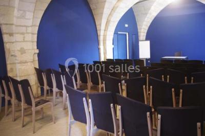 Salle voûtée avec murs en pierre, tables et chaises modernes, buffet en arrière-plan et éclairage chaleureux.
