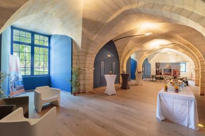 Salle voûtée avec murs en pierre, tables et chaises modernes, buffet en arrière-plan et éclairage chaleureux.