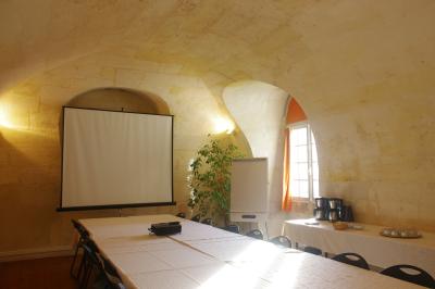 Salle voûtée avec murs en pierre, tables et chaises modernes, buffet en arrière-plan et éclairage chaleureux.