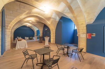 Salle voûtée avec murs en pierre, tables et chaises modernes, buffet en arrière-plan et éclairage chaleureux.