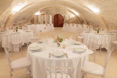 Salle voûtée avec murs en pierre, tables et chaises modernes, buffet en arrière-plan et éclairage chaleureux.