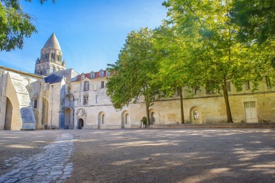 Miniature Location salle Saintes (Charente-Maritime) - Abbaye Aux Dames - La Cité Musicale #27 Jardin fleuri avec allée centrale et vue sur une église romane sous un ciel bleu clair.